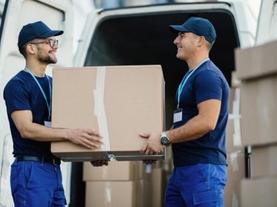 happy-manual-worker-cooperating-while-carrying-cardboard-boxes-delivery-van_637285-1258